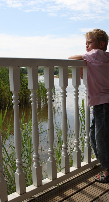 young-boy-leaning-railing-deck-outside